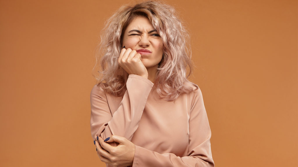 Woman holding on to her jaw as she contemplates whether she needs to see a root canal dentist or not 