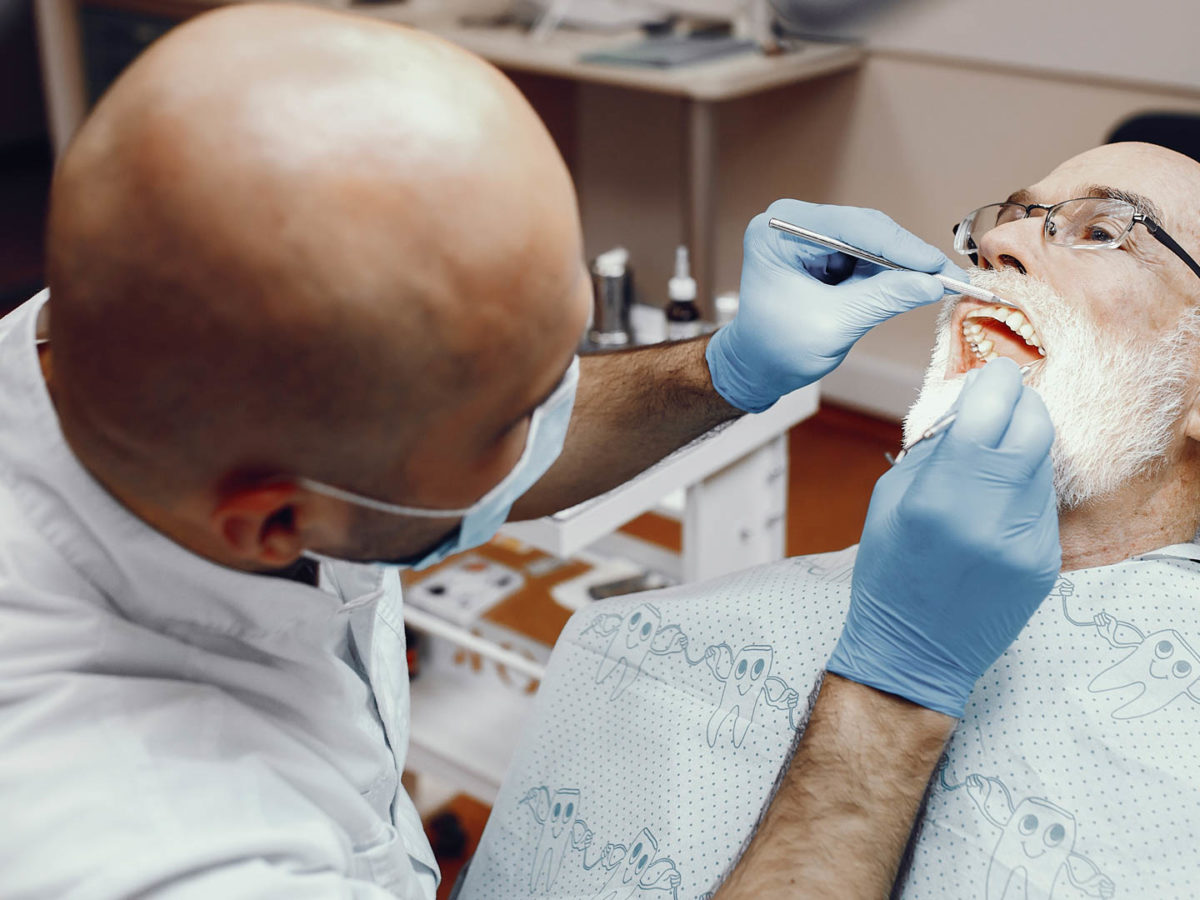 Image of dentist looking into patient's mouth to determine if they have gum disease.