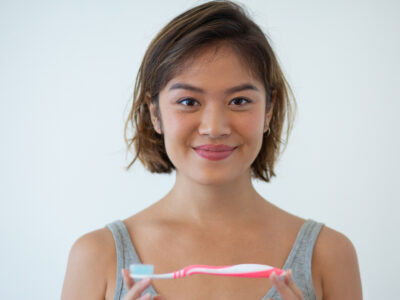 Image of girl smiling and holding a new toothbrush