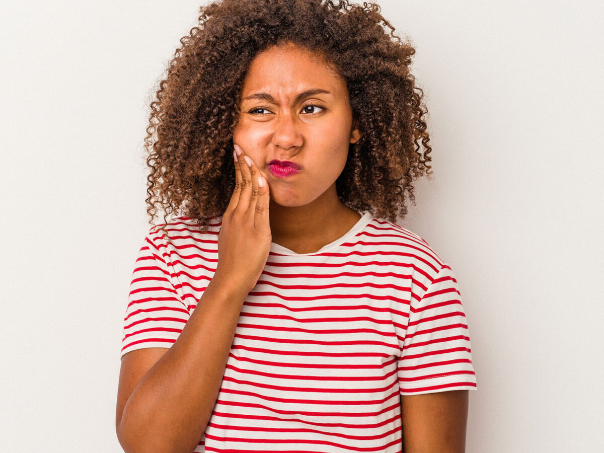 Woman holding her cheek wondering what to do when you have a severe toothache.